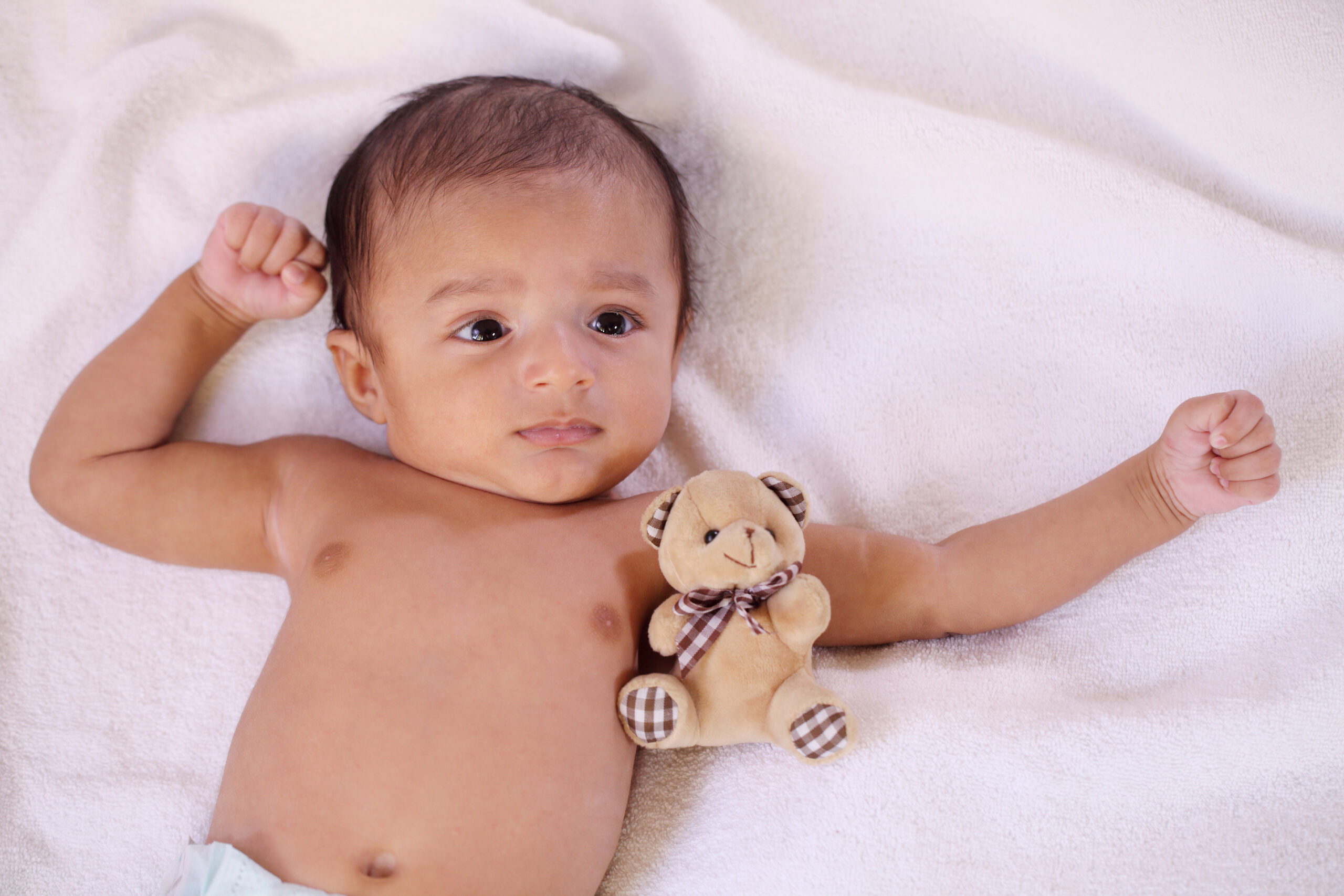 Newborn baby and teddy bear on bed