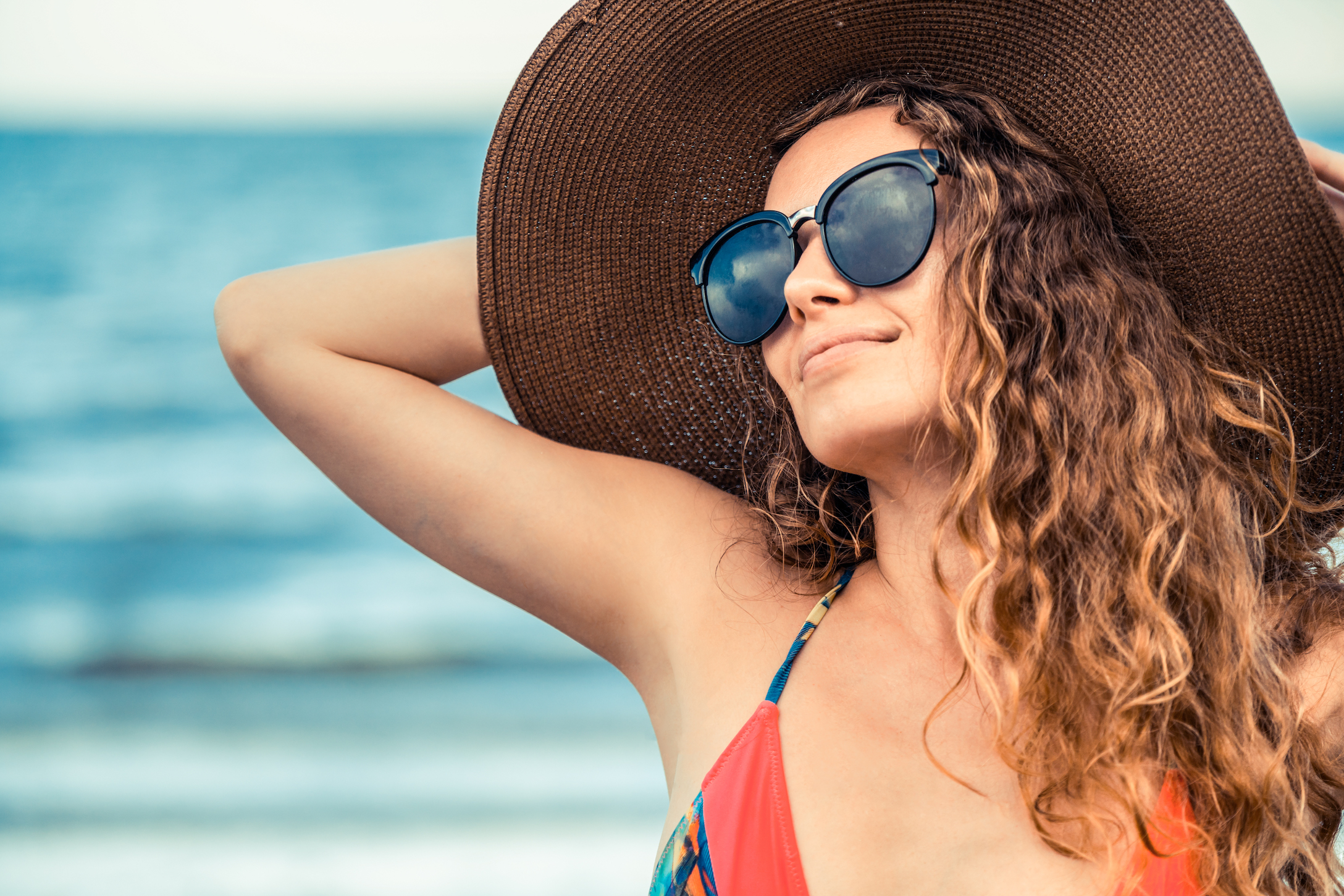 woman at the beach in a hat and sunglasses