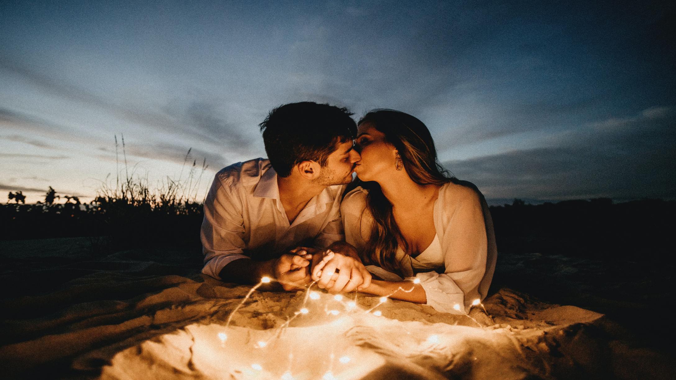 Couple outside kissing with twinkle lights