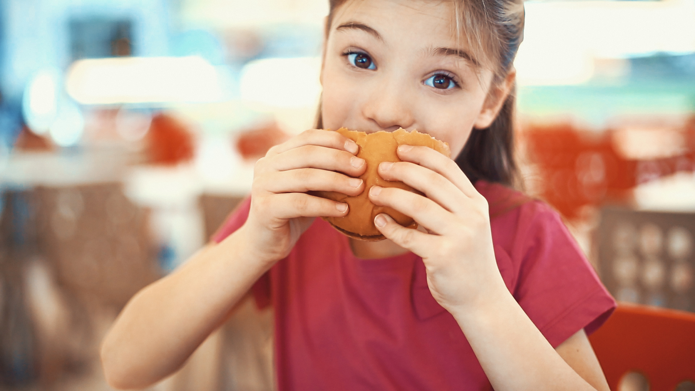 Little girl enjoying a burger.