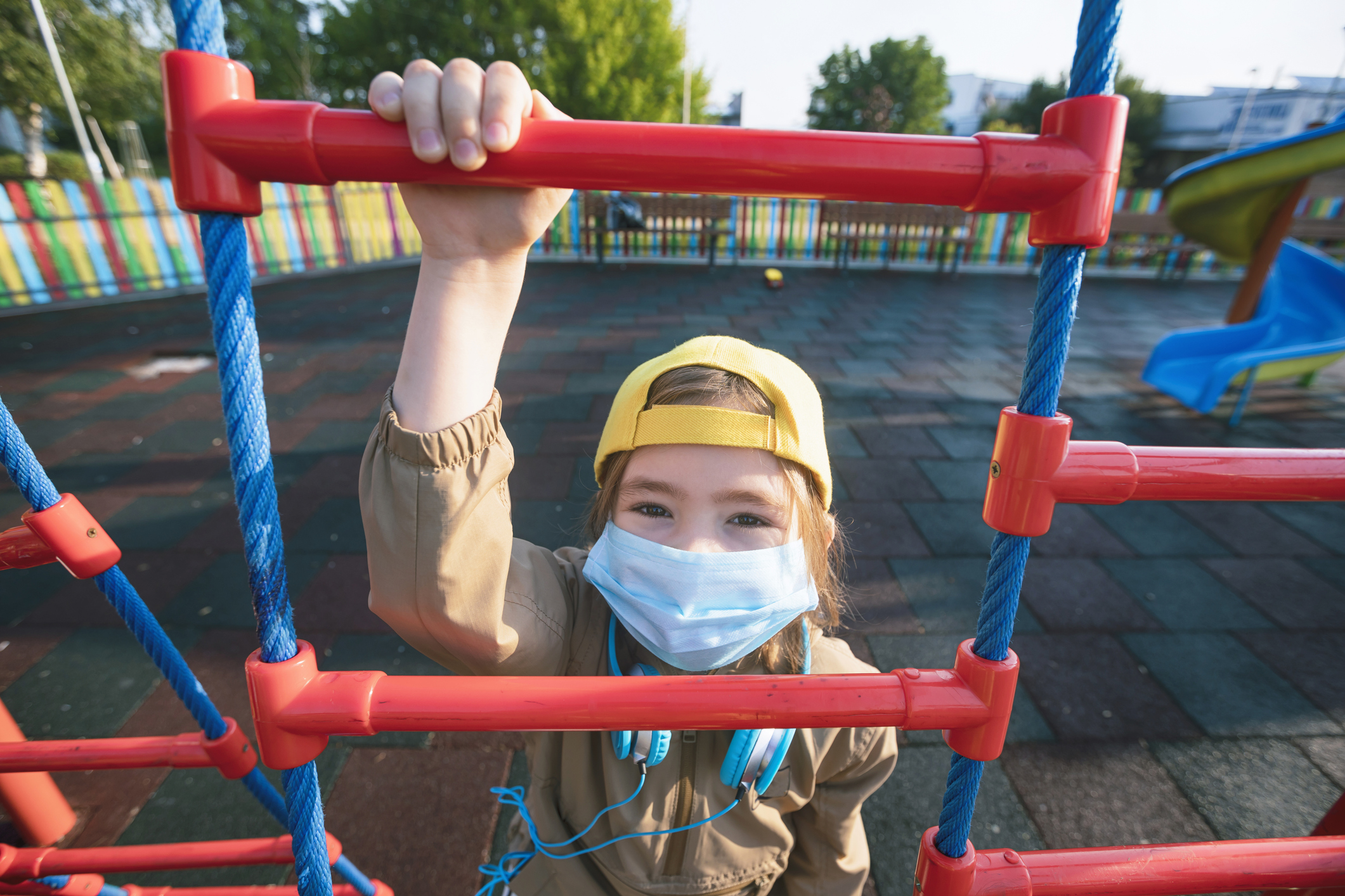 Little child in protective mask on a playground during the covid-19 epidemic