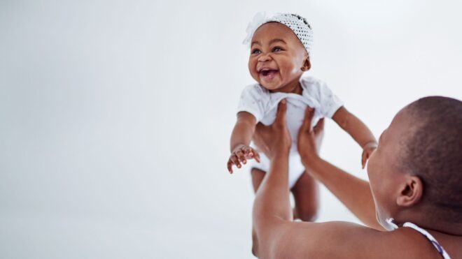mama holding her smiling baby in the air