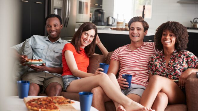 Millennial friends watch TV on the couch