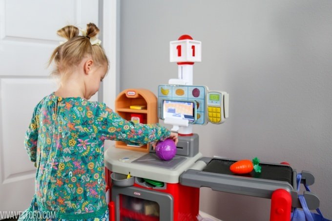 Little girl placing pretend groceries on conveyor belt