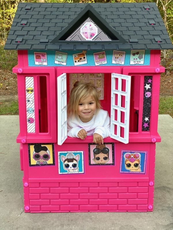 Little girl peeking out of LOL Surprise Cottage
