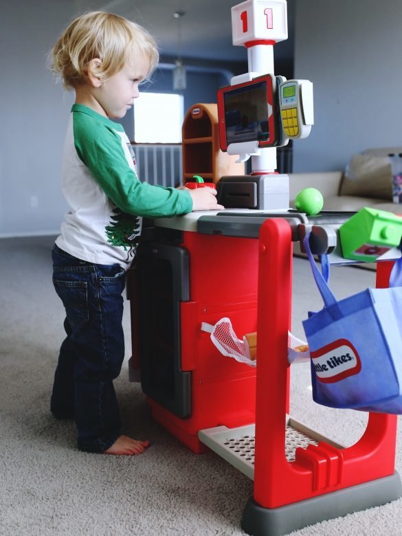 Toddler boy concentrating while playing with LIttle Tikes Smart Checkout