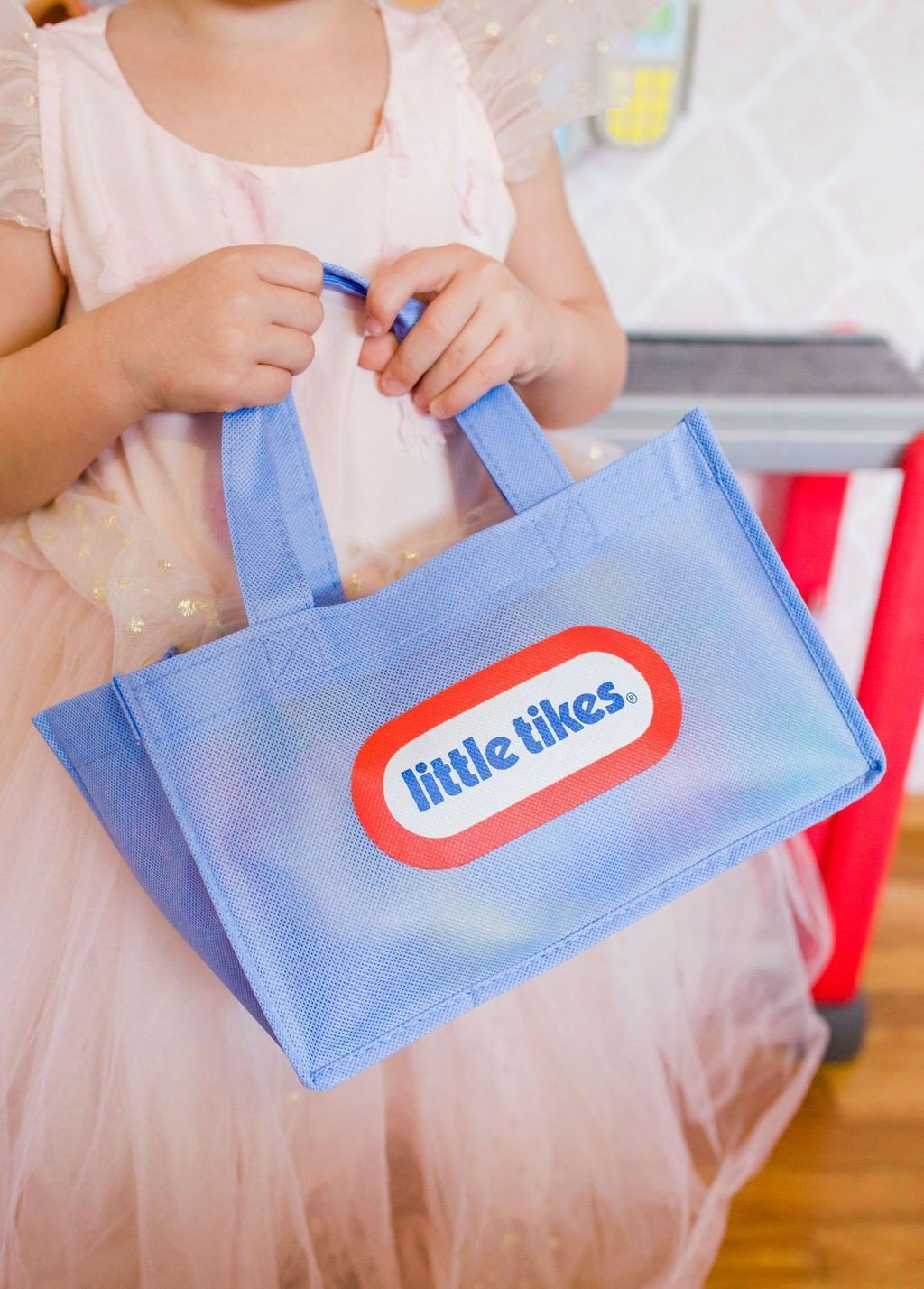 little girl holding Little Tikes shopping bag