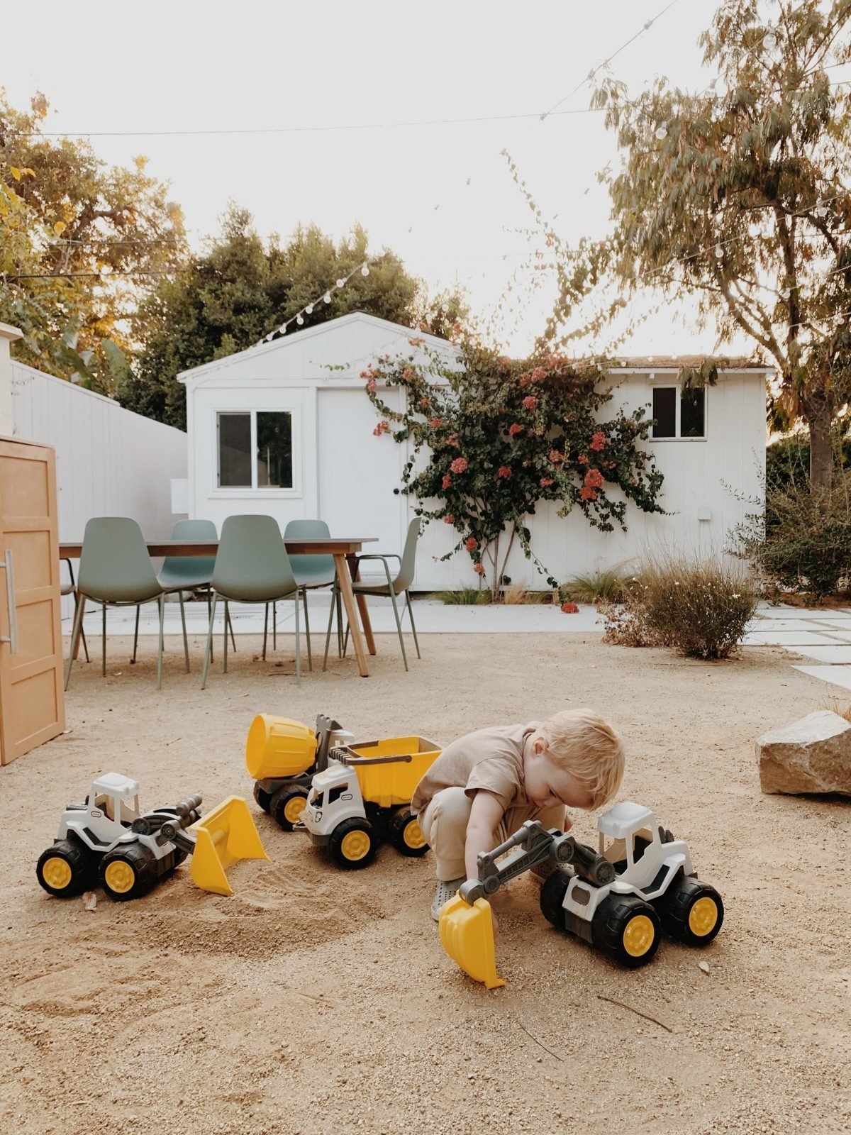 Toddler boy playing in dirt with Little Tikes trucks