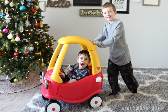 Big brother pushing toddler in Cozy Coupe