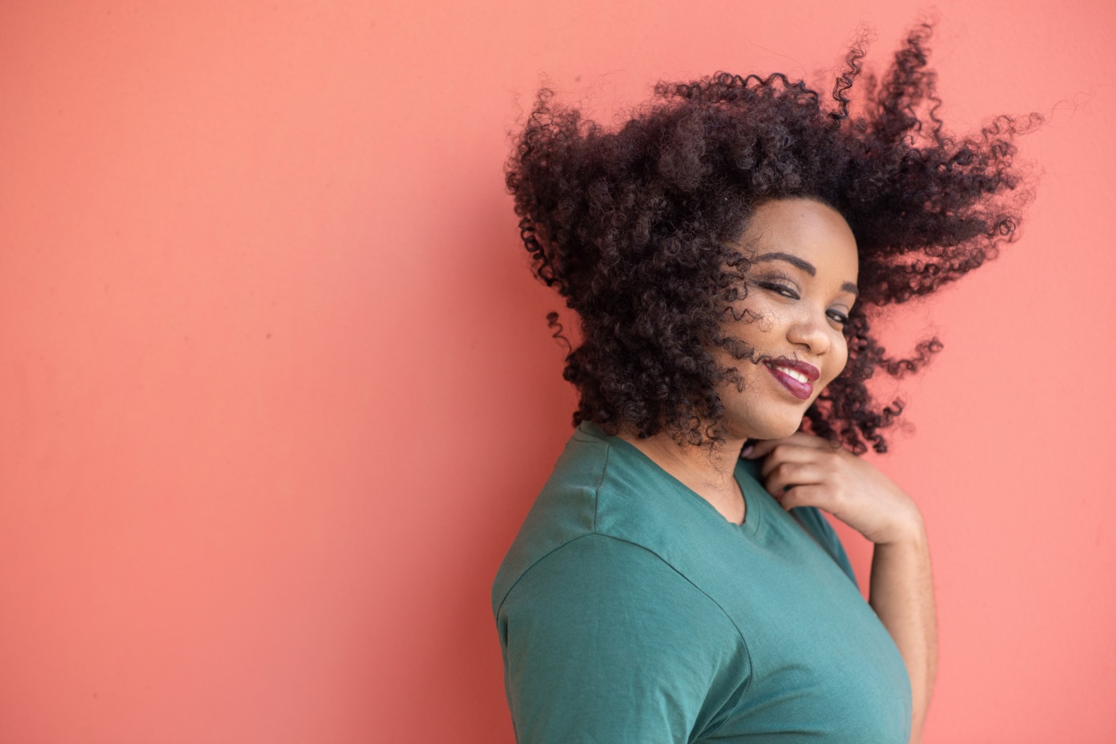 portrait-of-smiling-lady-with-curly-hair-standing-against-solid-background_t20_nRra2P.jpg