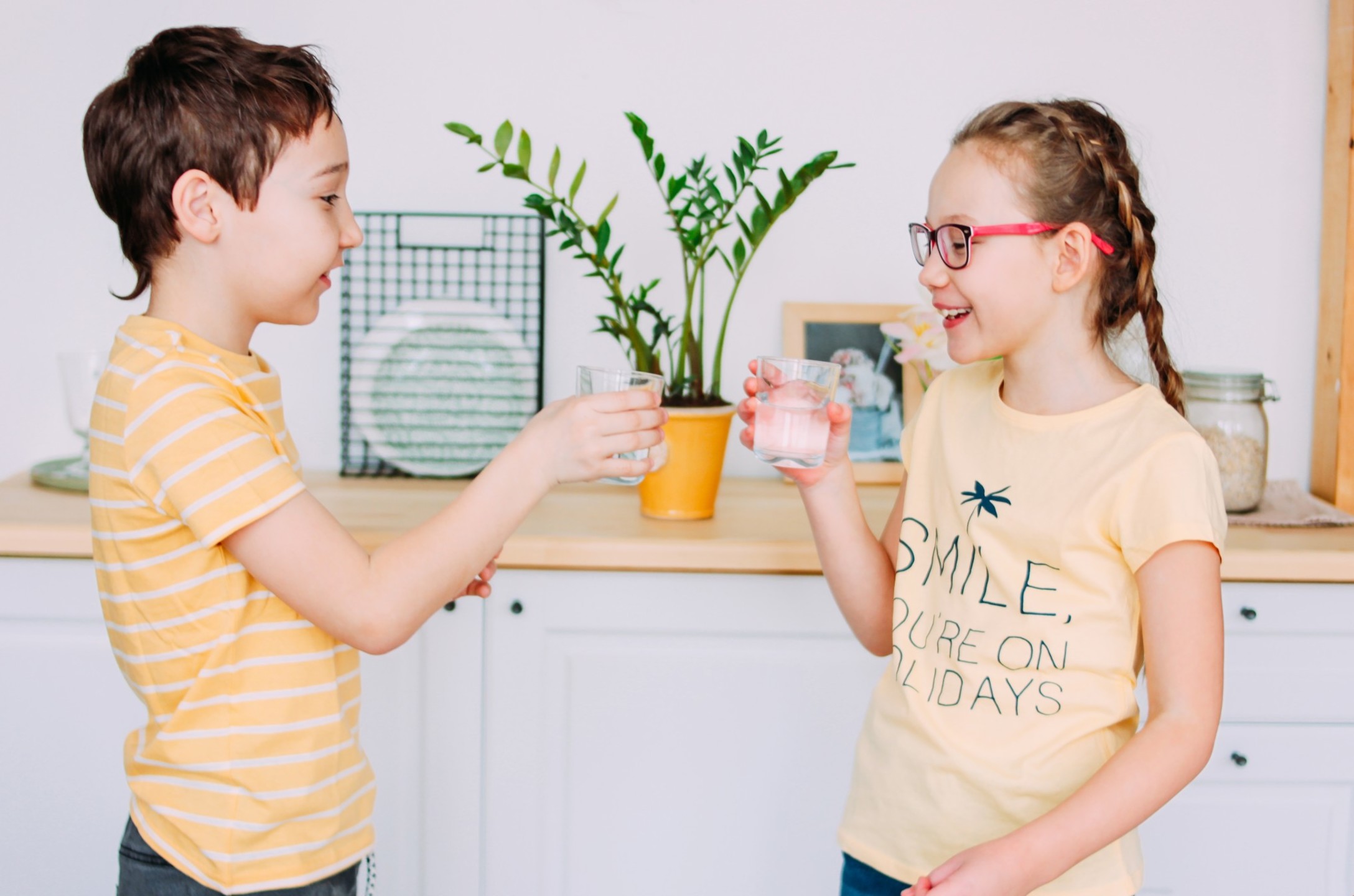 smiling-boy-and-girl-in-yellow-t-shirts-hold-glasses-of-clean-water-in-hands-at-kitchen_t20_nRxzOg.jpg