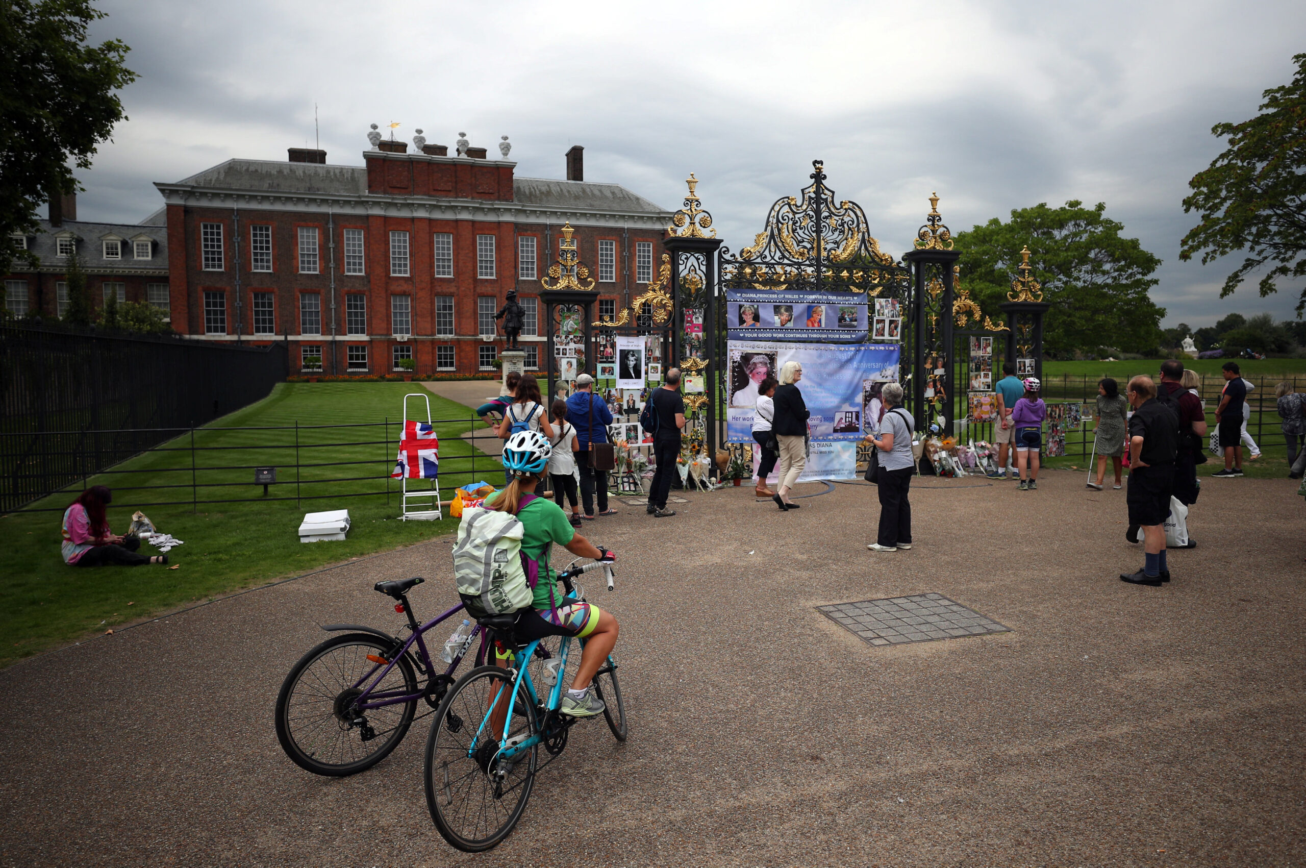 People look at flowers and tributes in memory of the late Princess Diana at the gates of her former residence Kensington Palace in London