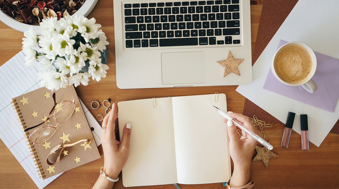 Young woman writing notes and working on a laptop