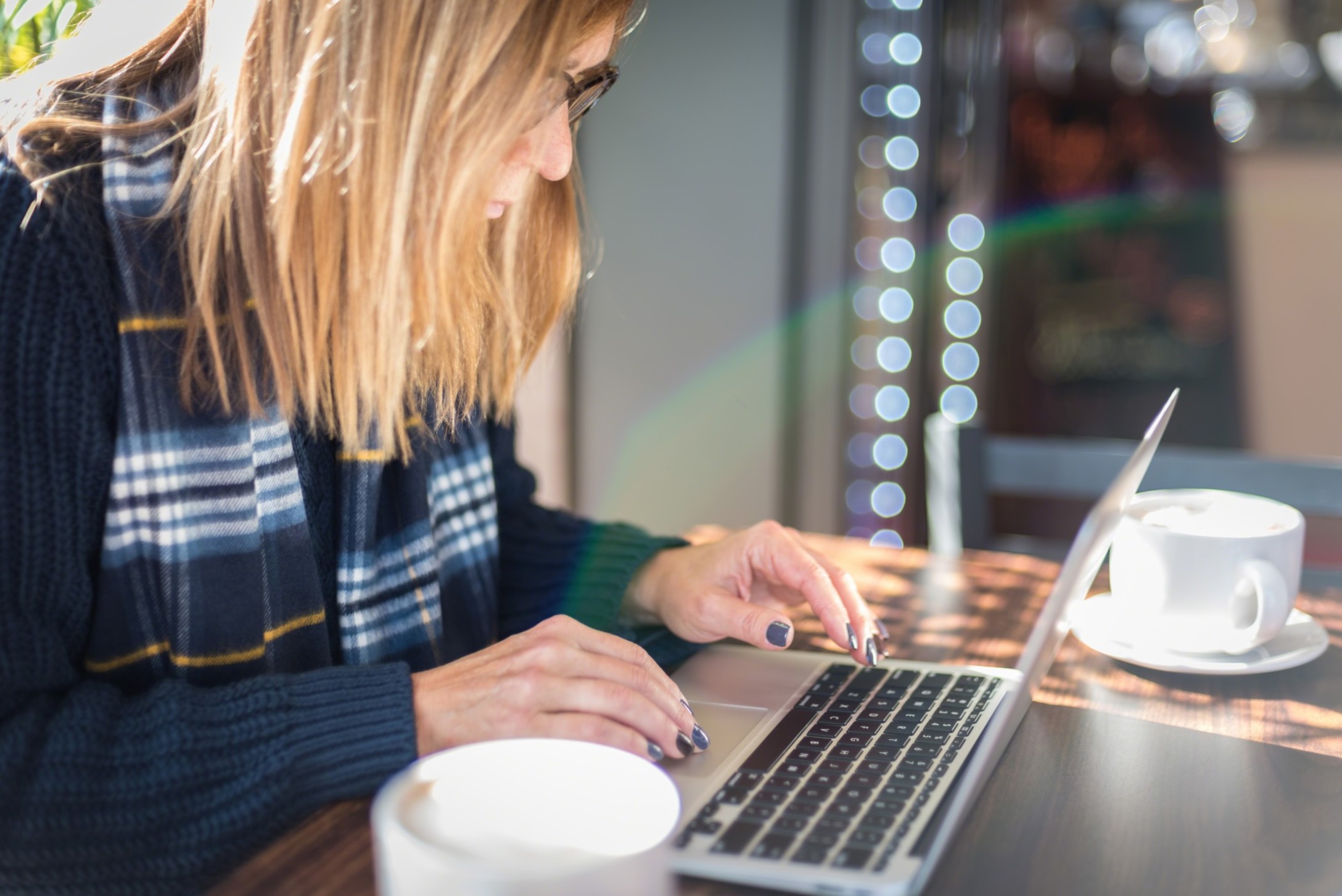 woman-using-laptop-in-coffee-shop-with-lens-flare-rainbow-computer-typing-keyboard-close-up-closeup_t20_eoOWm2-1.jpg