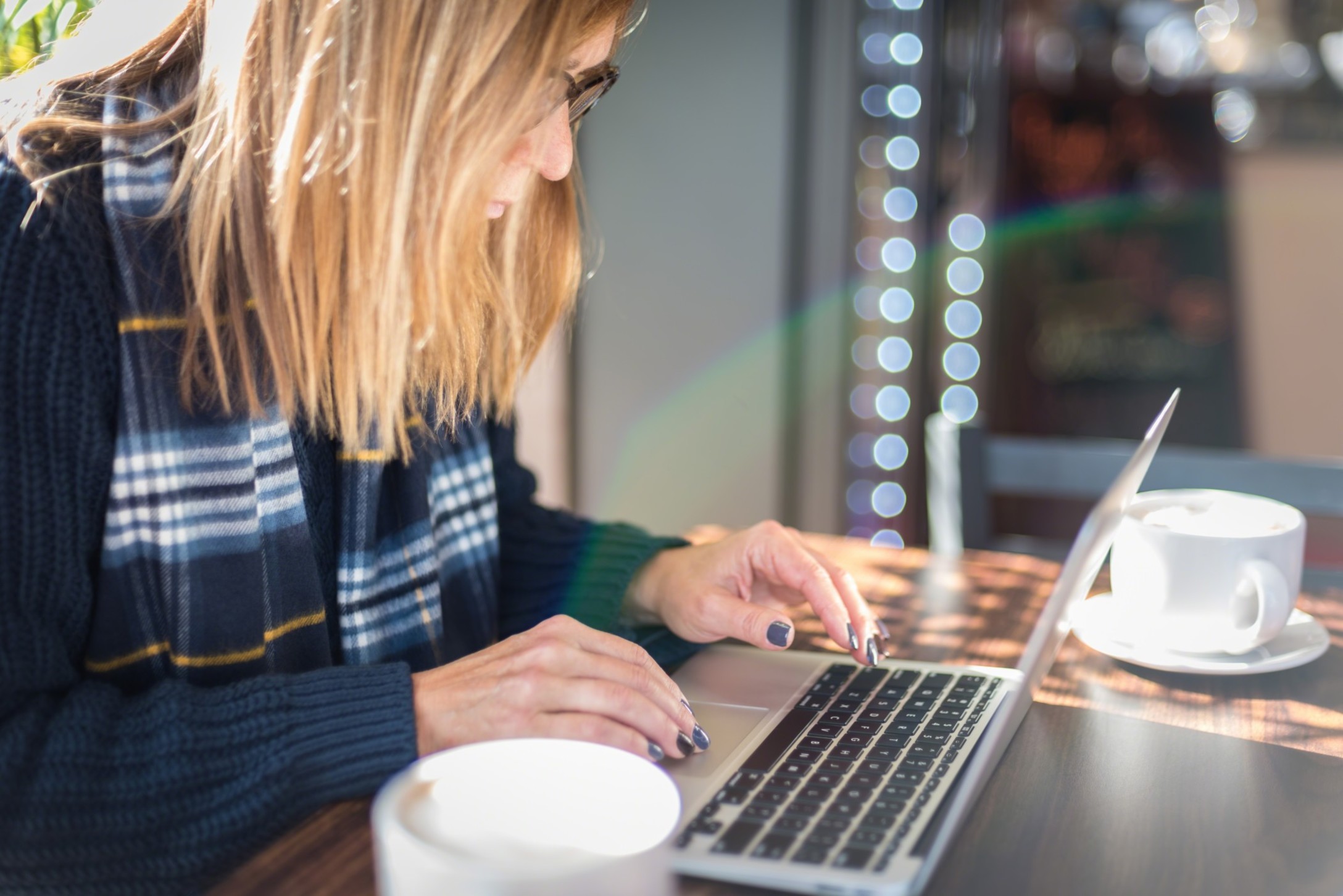 woman-using-laptop-in-coffee-shop-with-lens-flare-rainbow-computer-typing-keyboard-close-up-closeup_t20_eoOWm2-2.jpg