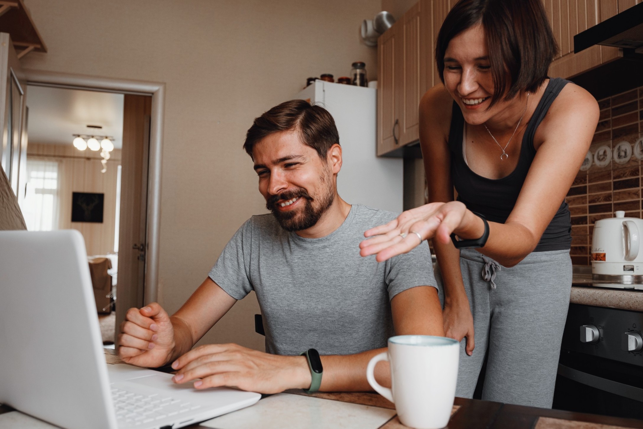 young-couple-using-laptop-and-smartphone-in-the-kitchen-smiling-man-working-online-at-home-family_t20_e9zvym.jpg