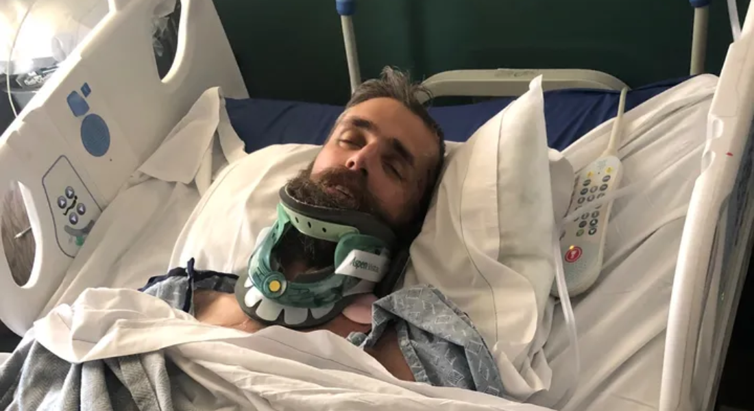 Brandon Greene with a neck brace in a hospital bed