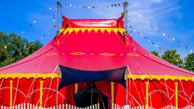 red and yellow circus tent with a white fence and banners