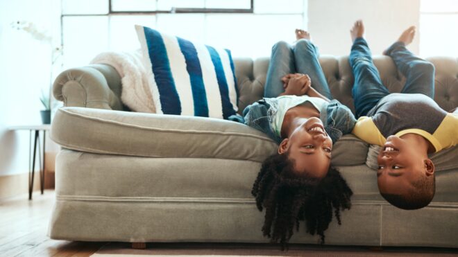 Siblings hanging upside down on a couch