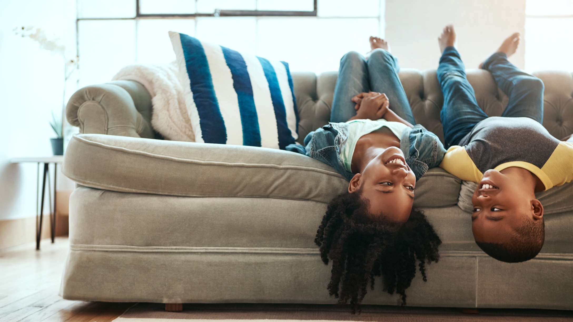 Siblings hanging upside down on a couch