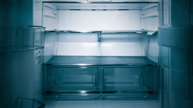empty refrigerator with the inside lit in a dark room