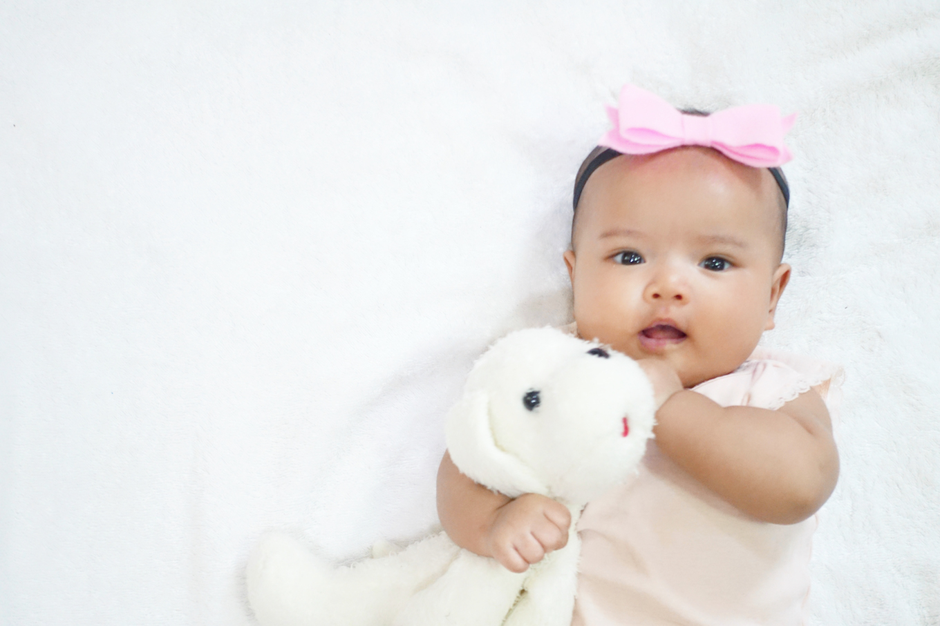 Newborn baby girl hug and cuddling her dog doll on white background