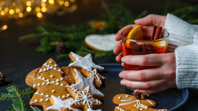 On a black tray is a glass of mulled wine, which the girl holds with both hands