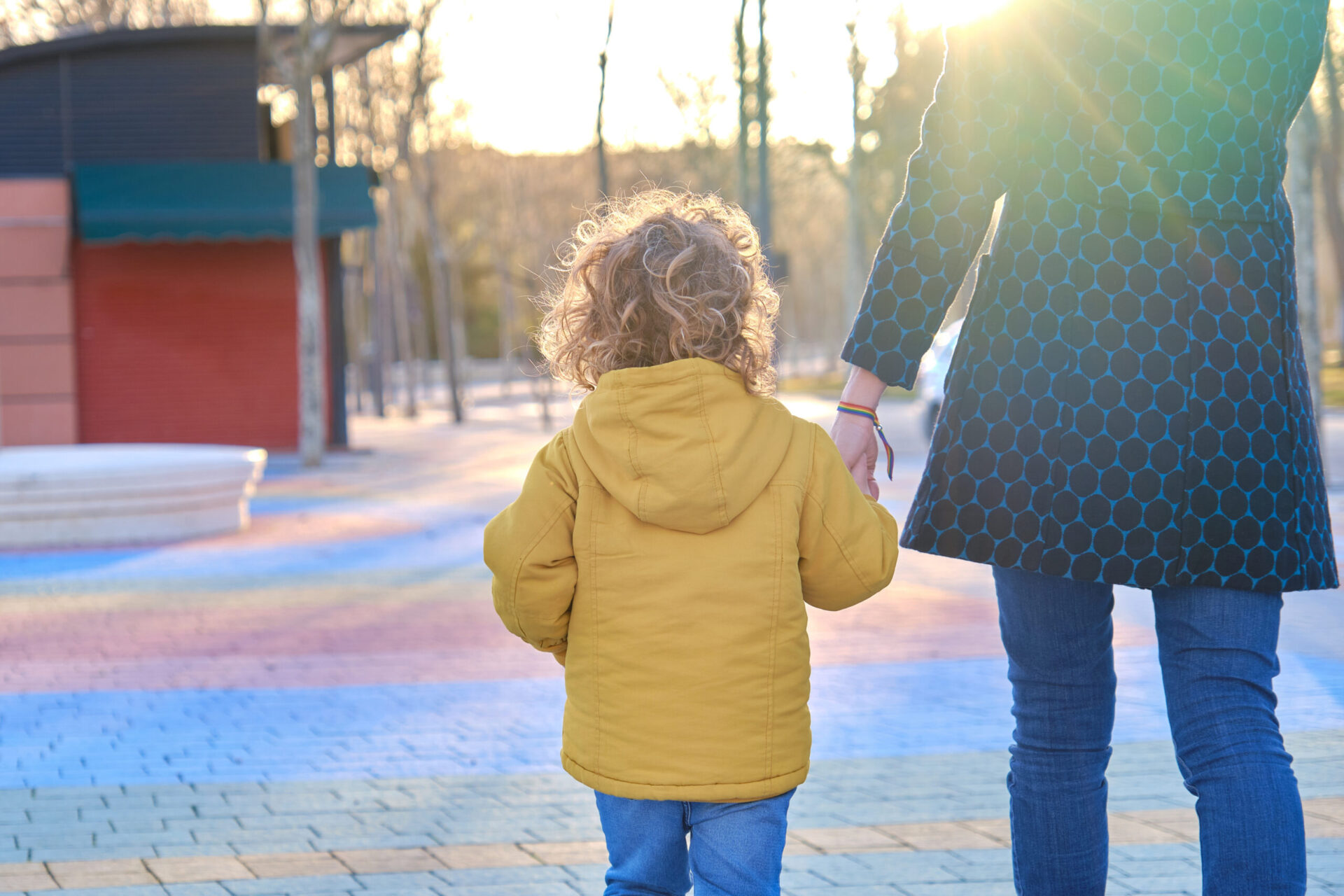 A mother walking hand in hand with her young son enjoying a moment of family togetherness in a park at sunset.