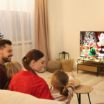 Happy family spending time together near TV in cosy room. Christmas atmosphere