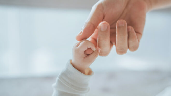 Baby holds parent's hand