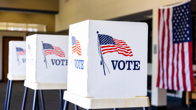 three voting booths in front of an American flag