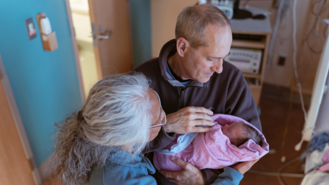 grandparents holding newborn in the hospital room