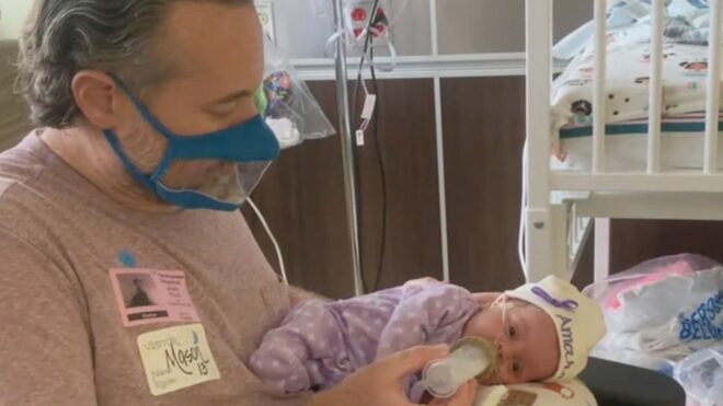 Parent with clear face mask feeding baby
