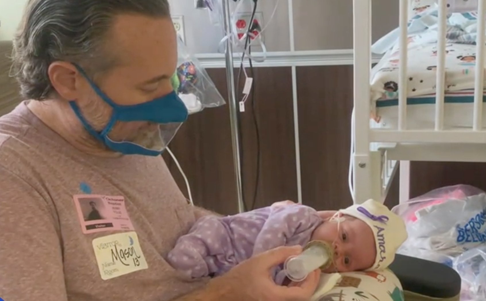 Parent with clear face mask feeding baby
