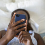 Teenage girl using a phone while lying on her bed