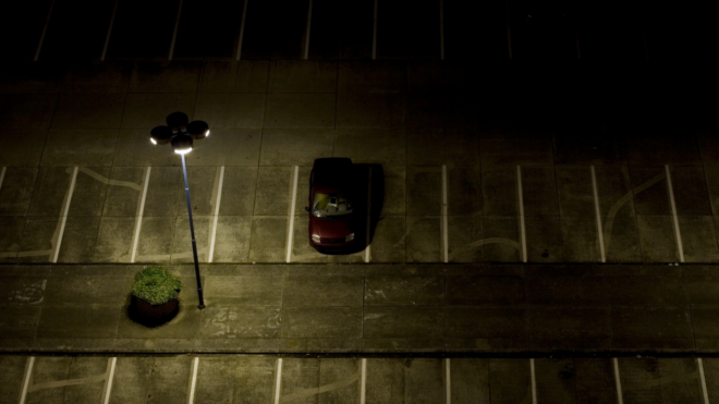 a red car in an empty parking lot at night