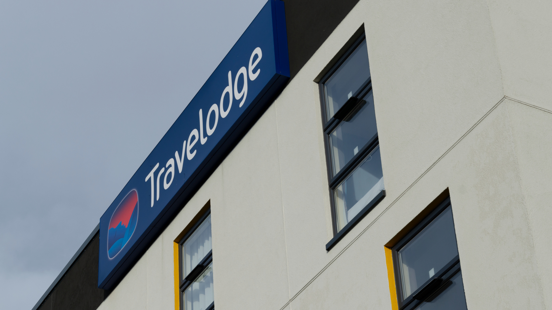 a white building with a blue sign saying Travelodge in white letters