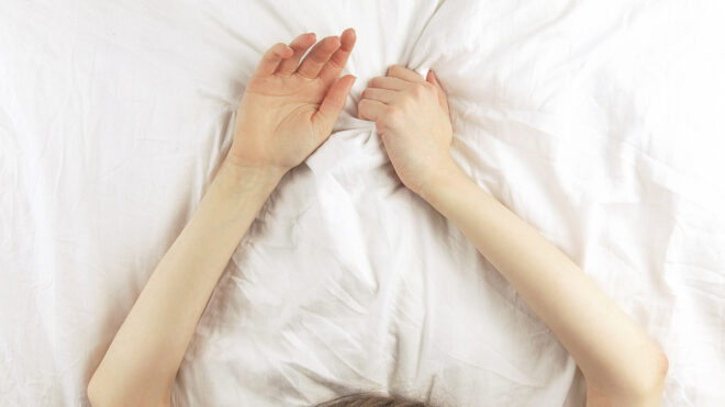 woman grabbing sheets in pleasure while in bed