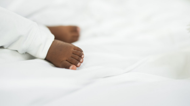 Black baby's feet on a white blanket