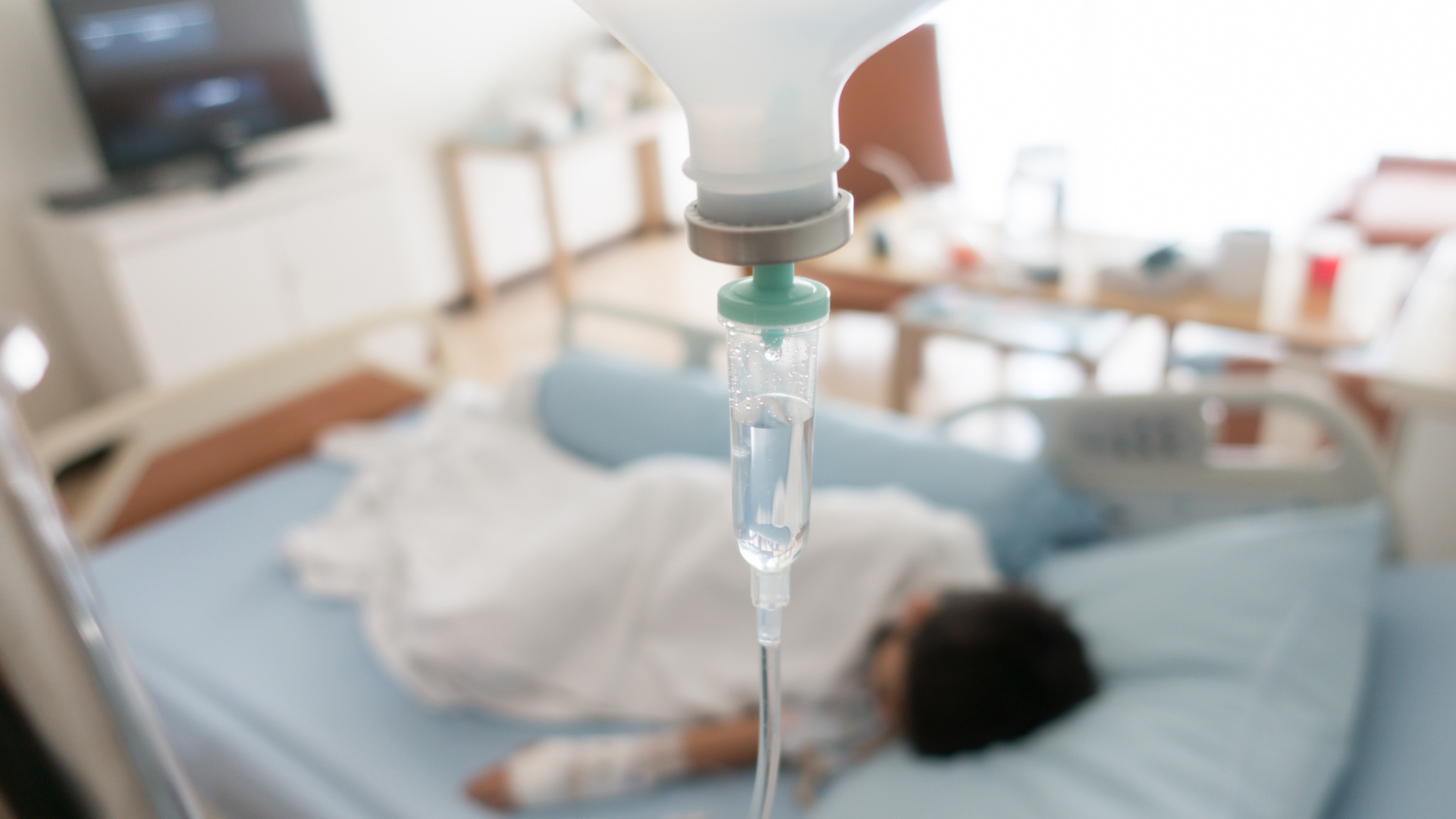out of focus image of child laying in hospital bag hooked up to i.v. bag