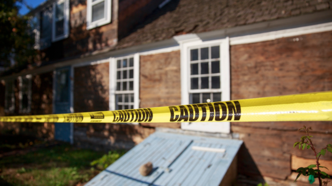 brown house with white windows blocked by yellow police caution tape