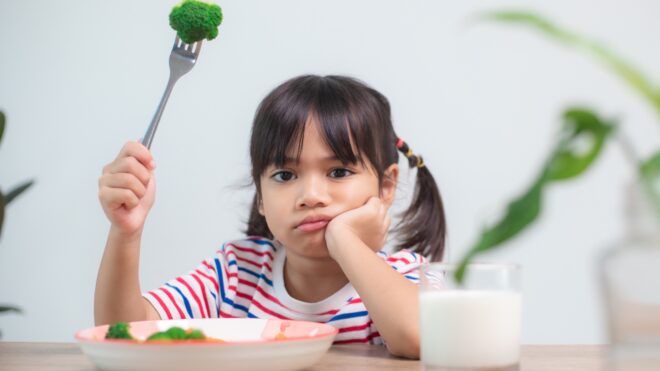child refusing to eat food at the dinner table