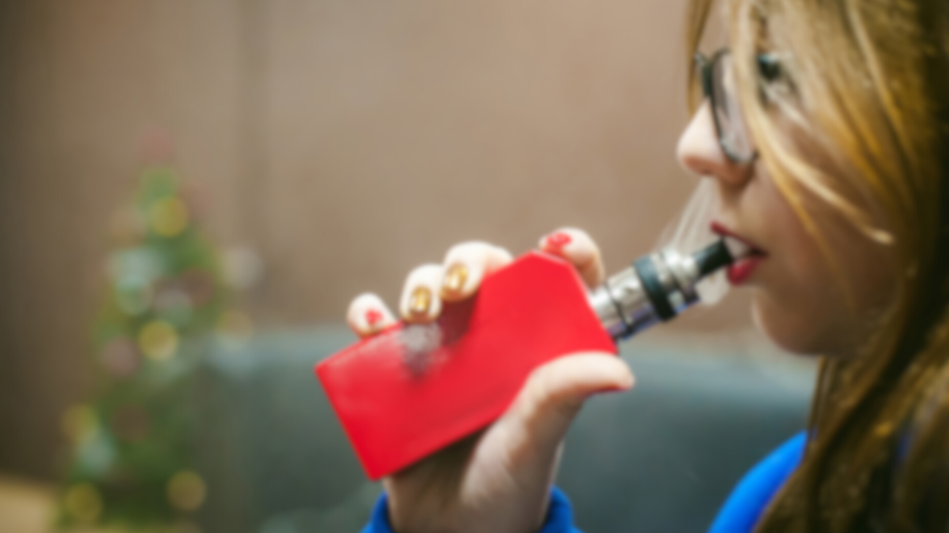 a young girl with long hair and glasses holding and smoking a red vape
