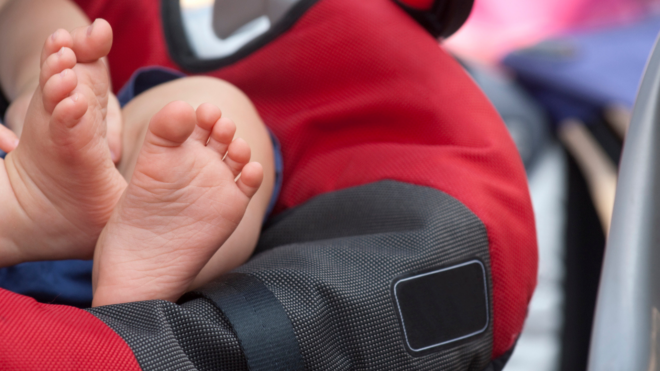 baby's feet in red car seat