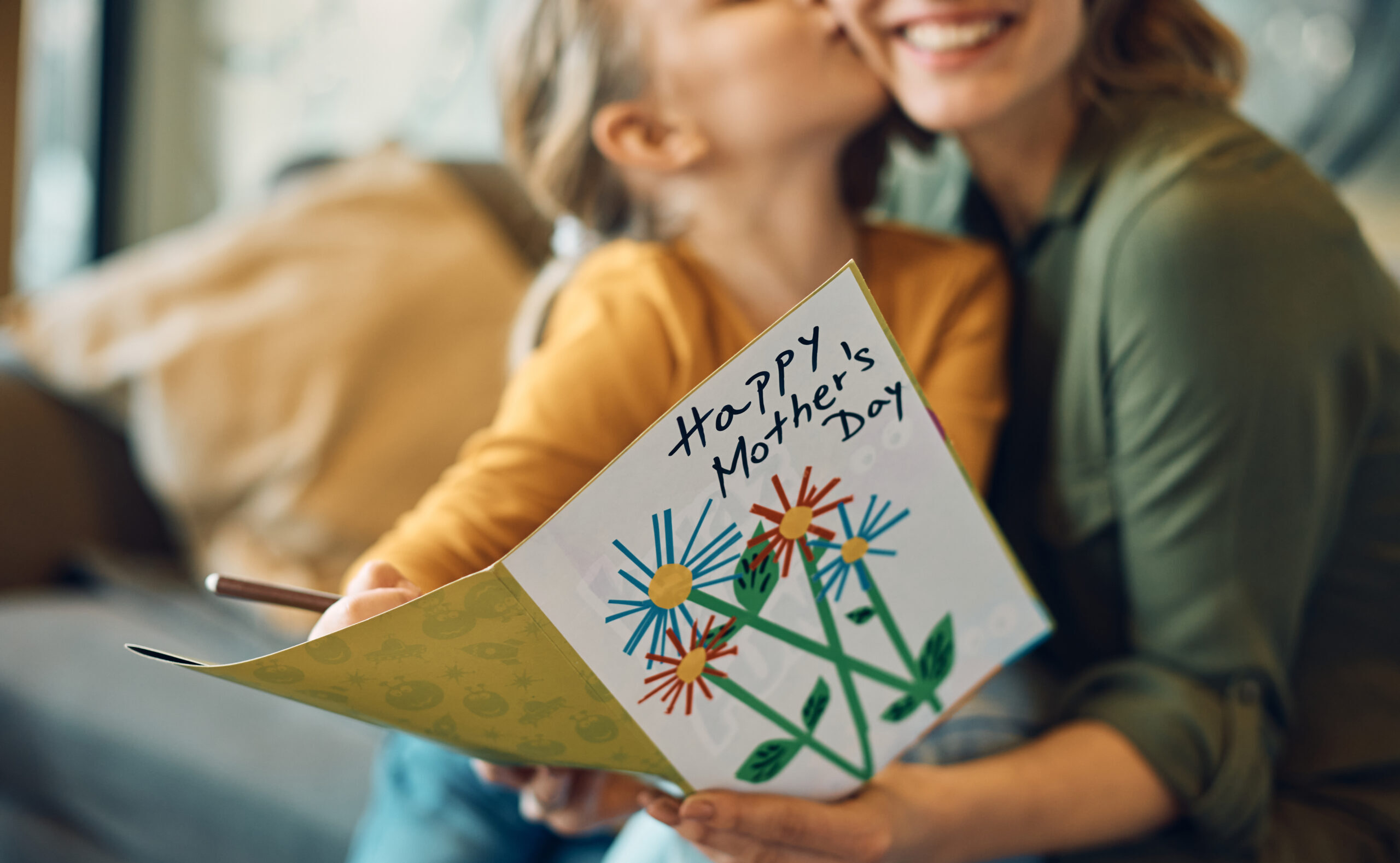 Close-up of woman receiving greeting card from her daughter on Mother's day.