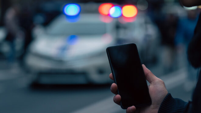 Holding a phone in front of police cars