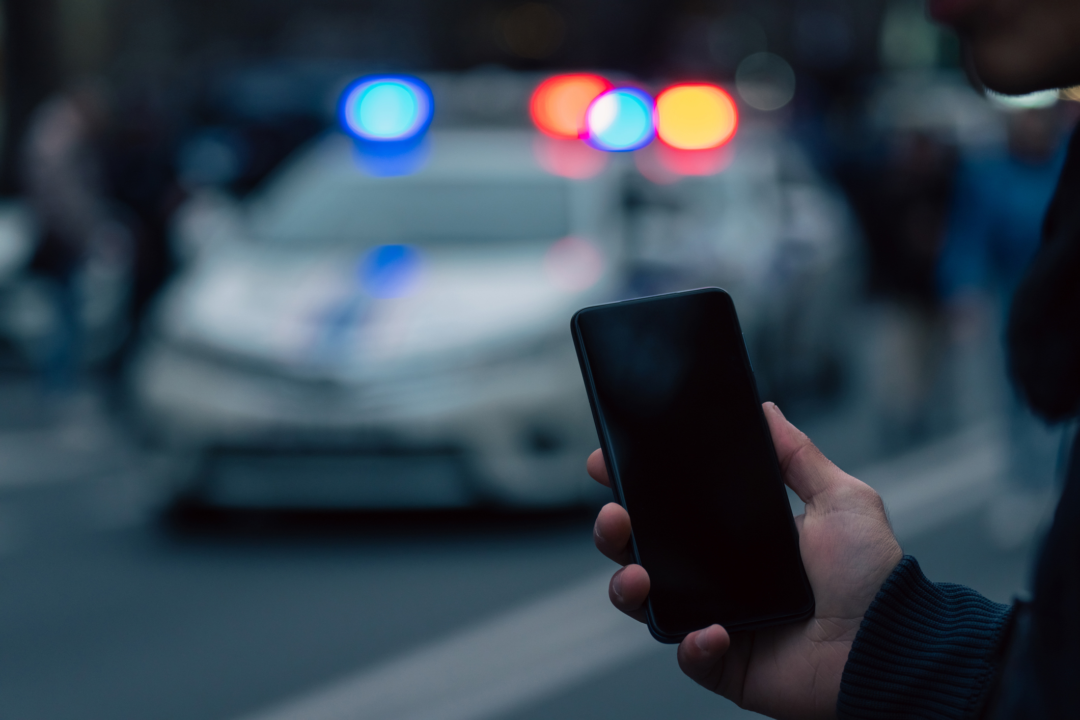 Holding a phone in front of police cars