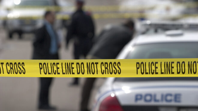 Long lens, crime scene. Detectives and officer in background.