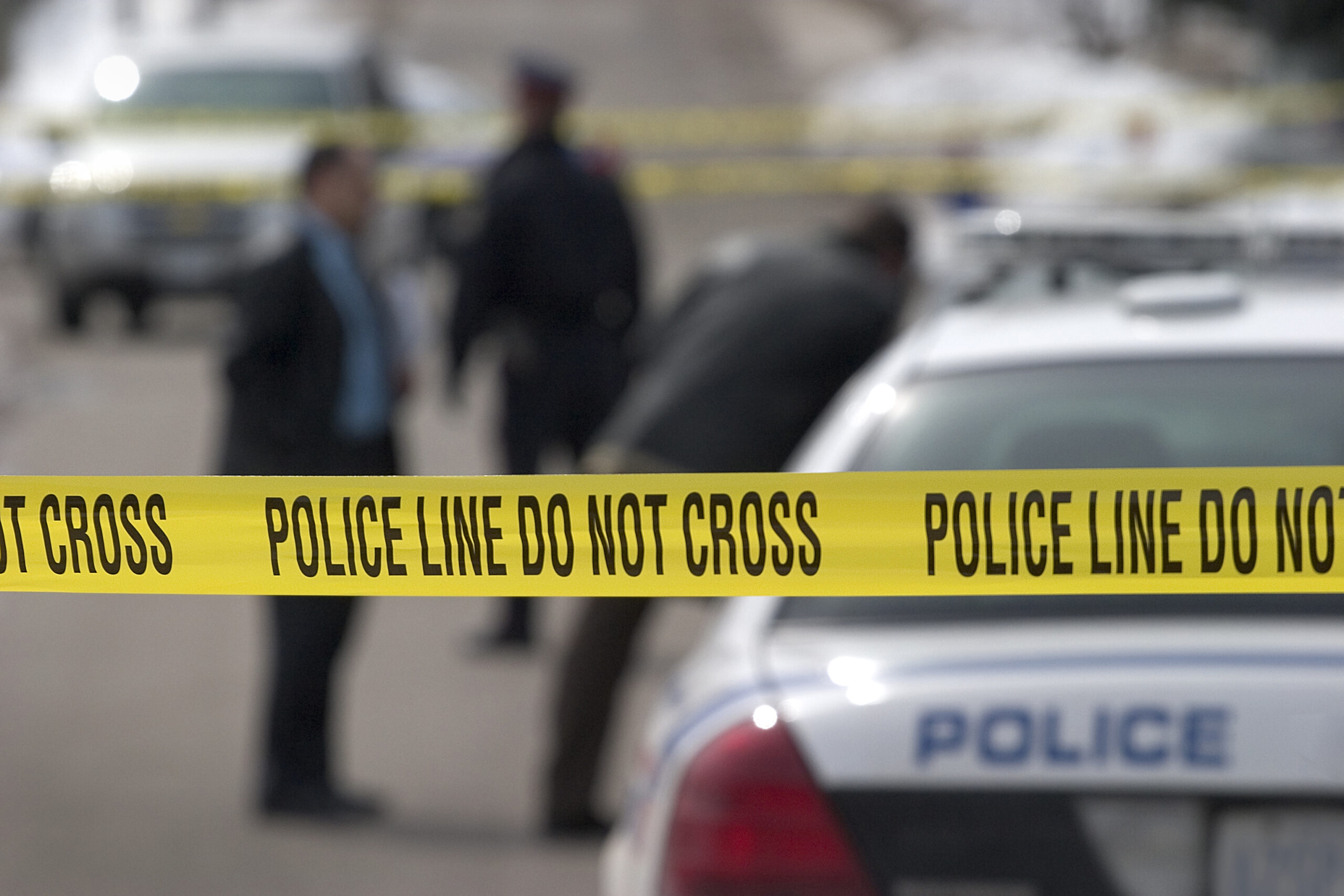 Long lens, crime scene. Detectives and officer in background.