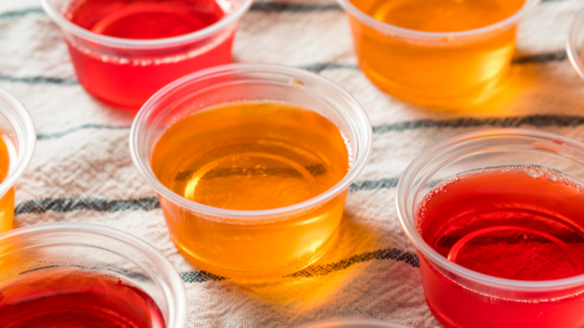 red and orange jello shots placed on top of a striped cloth